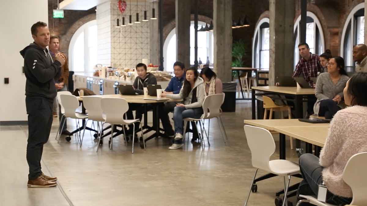 Employees gather and listen to a speaker.