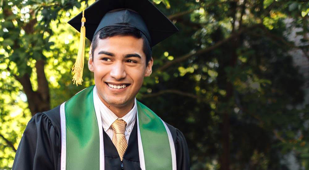 A smiling graduate wearing a cap and gown.